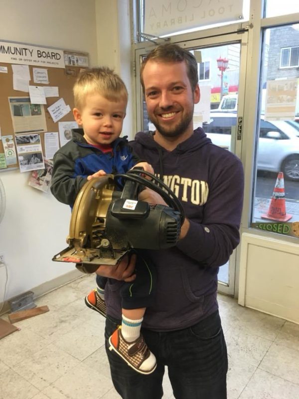 man holding toddler with circular saw