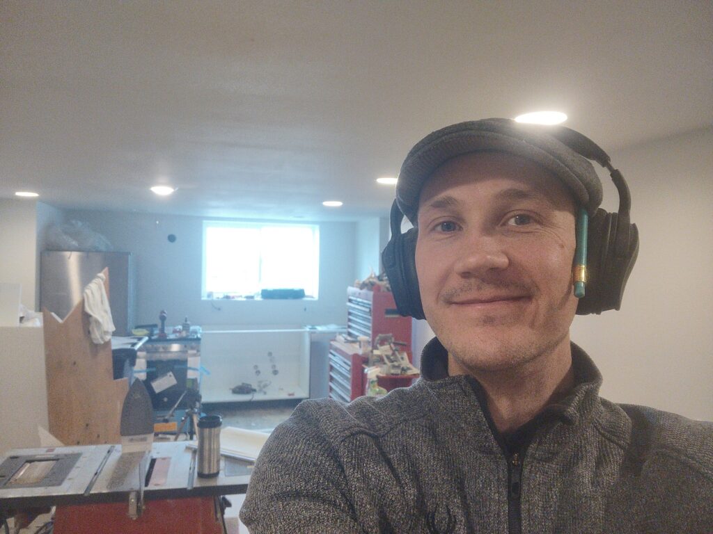 Paul Prociv smiling at the camera. Paul is a white man wearing a hat and headphones.